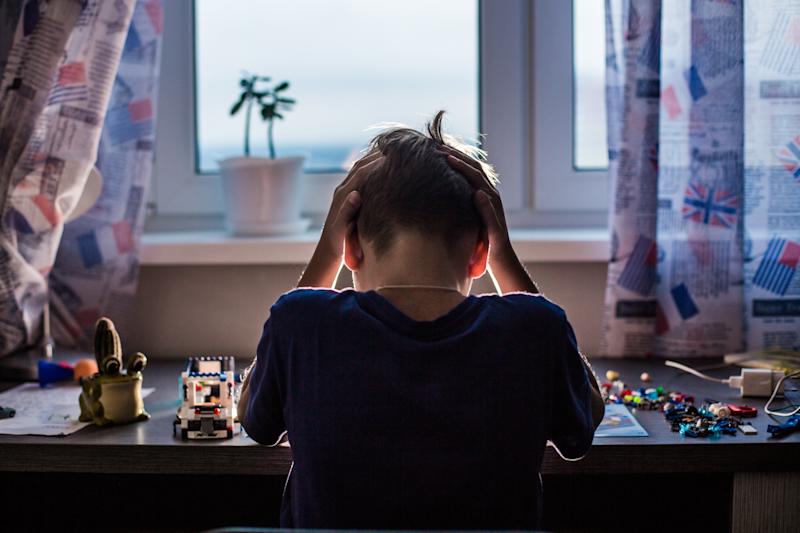A child sits at a desk with their head in their hands